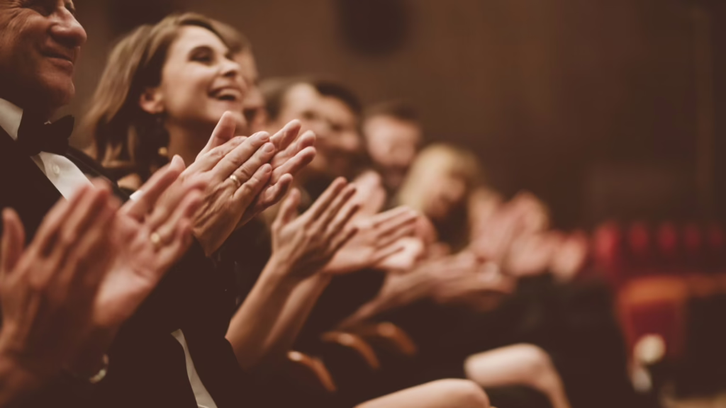 Public qui applaudit lors d’un événement culturel réussi.