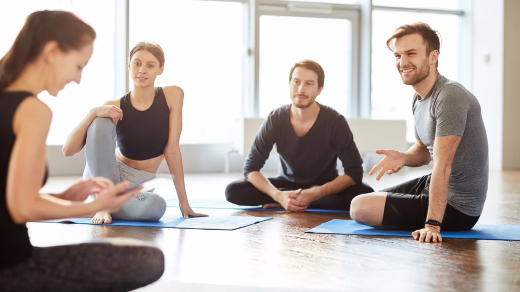 Professeur et élèves discutant sur le sol du Studio de yoga